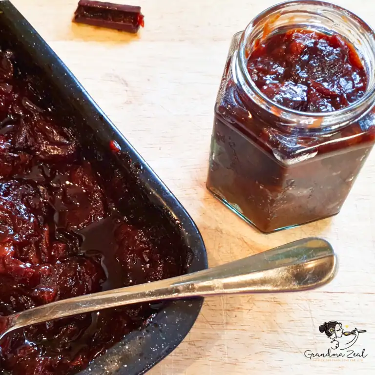 Thick, sugar-free plum butter shown in a deep baking tray with a glass jar filled beside it