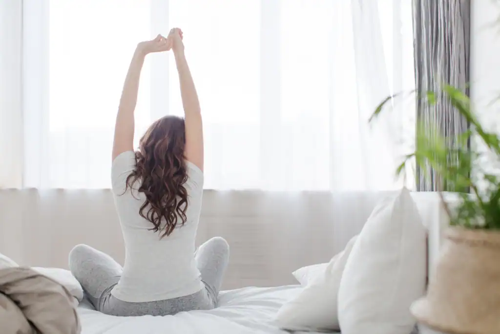 Woman stretching in morning light, symbolising renewal, movement, and the energy that comes from starting the day with intention.