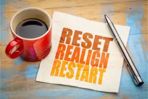 Red coffee mug beside a napkin with the words Reset, Realign, Restart, representing a fresh start and how to reset your mind and energy.