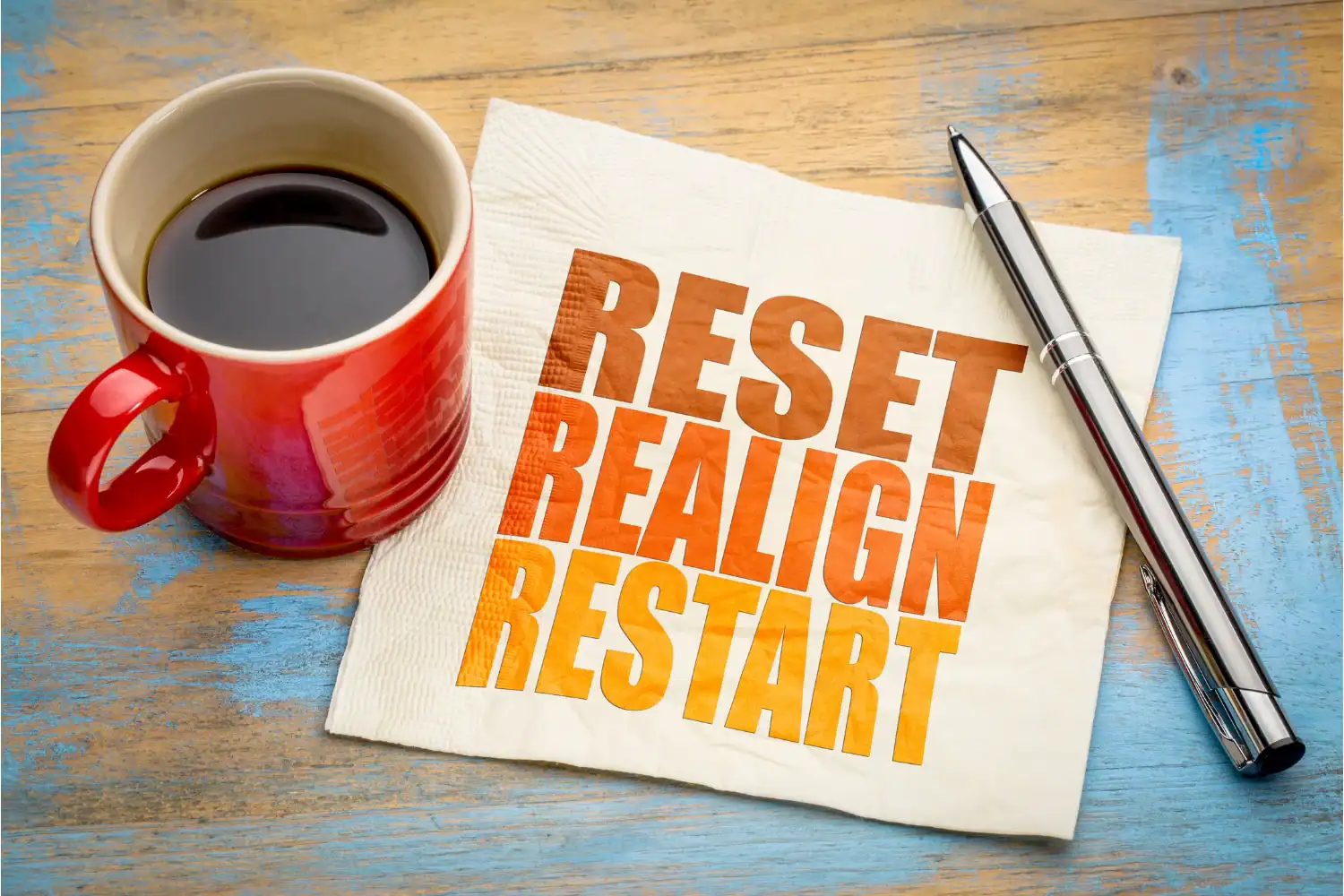 Red coffee mug beside a napkin with the words Reset, Realign, Restart, representing a fresh start and how to reset your mind and energy.
