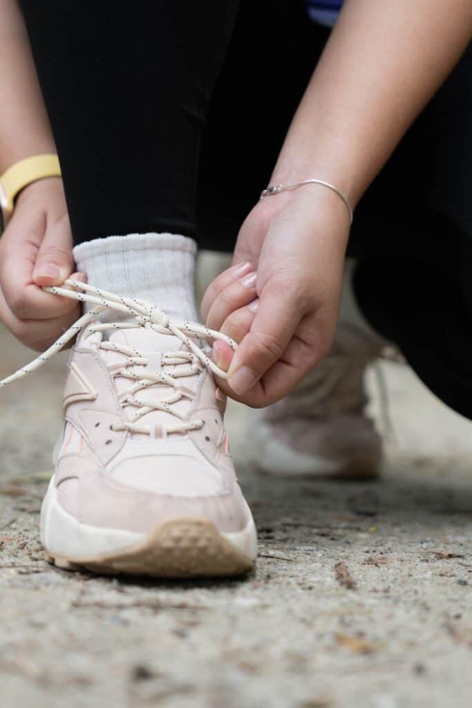 Hands tying walking shoes as a simple way to stay active in daily life. Title: