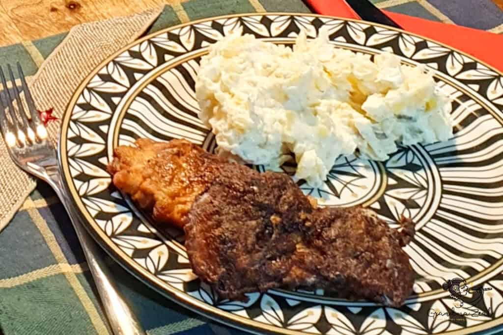 Classic potato salad served with crispy fried chicken on a patterned plate