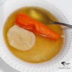 a bowl of chicken and bone soup with carrot and turnip