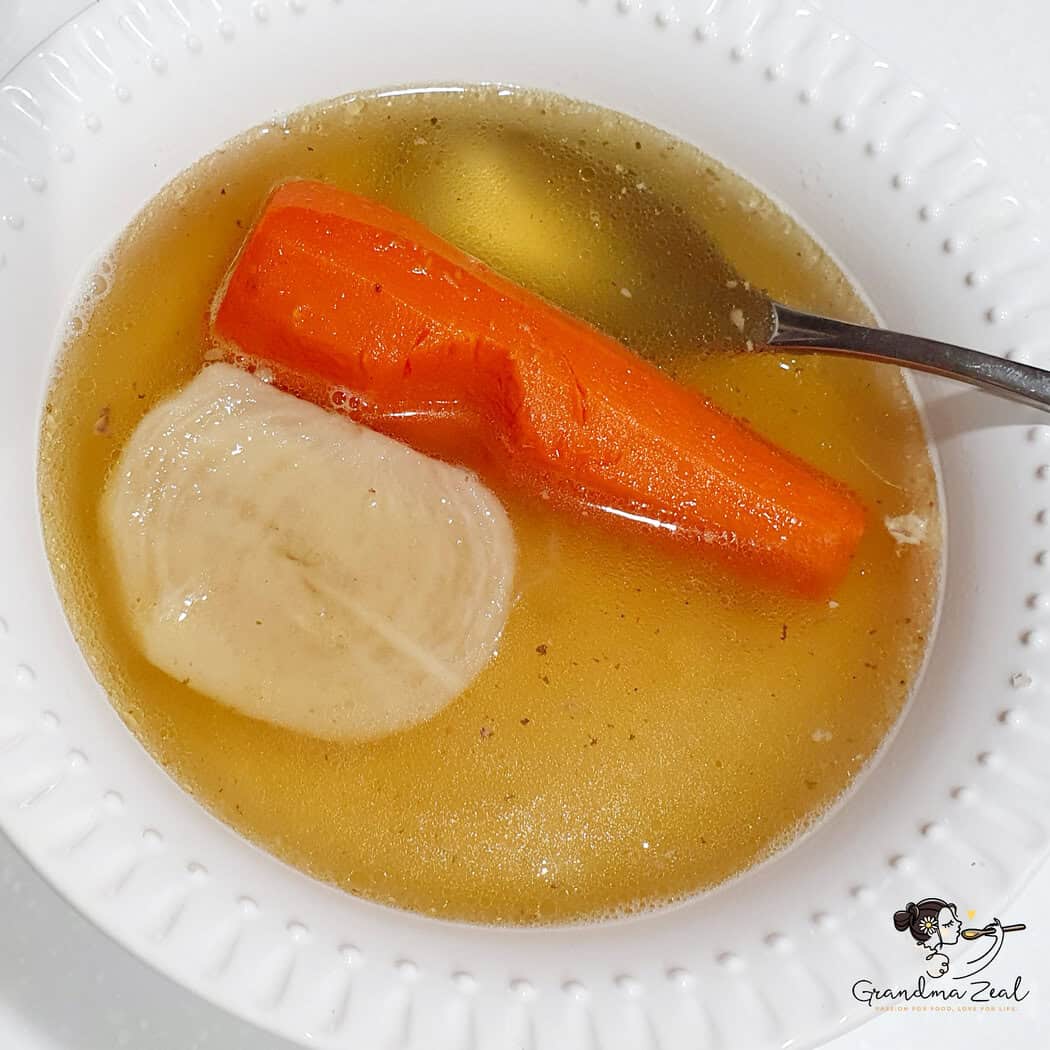a bowl of chicken and bone soup with carrot and turnip