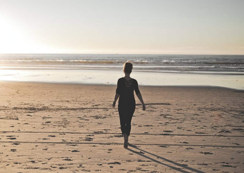 Silhouette of a woman standing on a beach, representing strength, independence and confidence in later life.